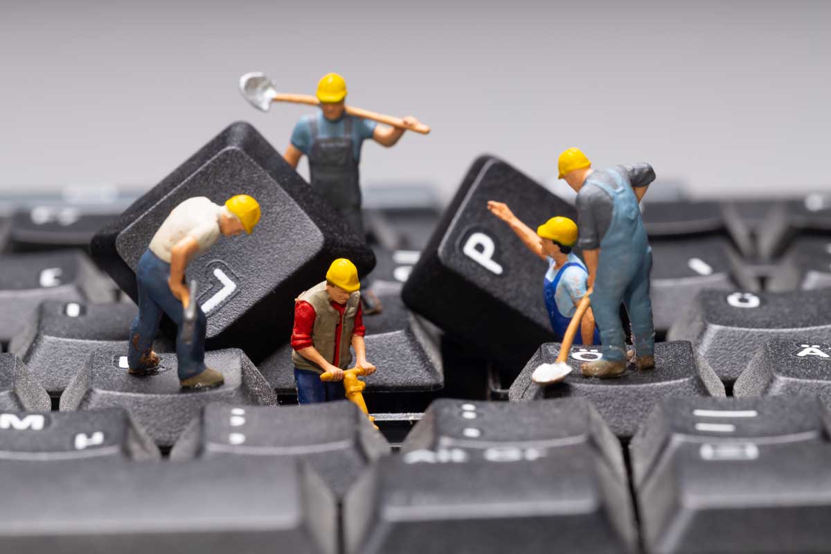 Team of mini figurines repairing a keyboard
