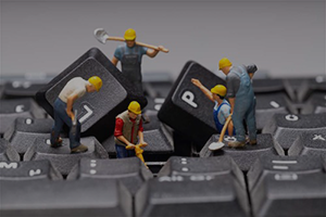 mini figurines construction workers taking apart a keyboard